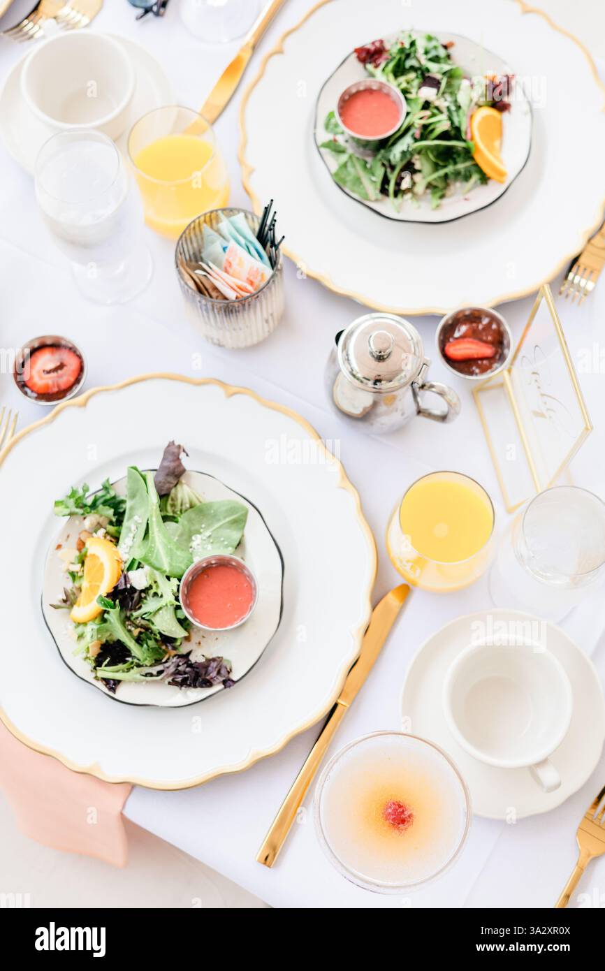 Elegant table setting with salad, orange juice, and silverware. Stock Photo