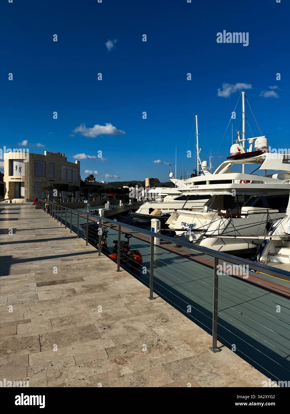 Luxury yachts docked at a marina under a clear blue sky in a coastal ...