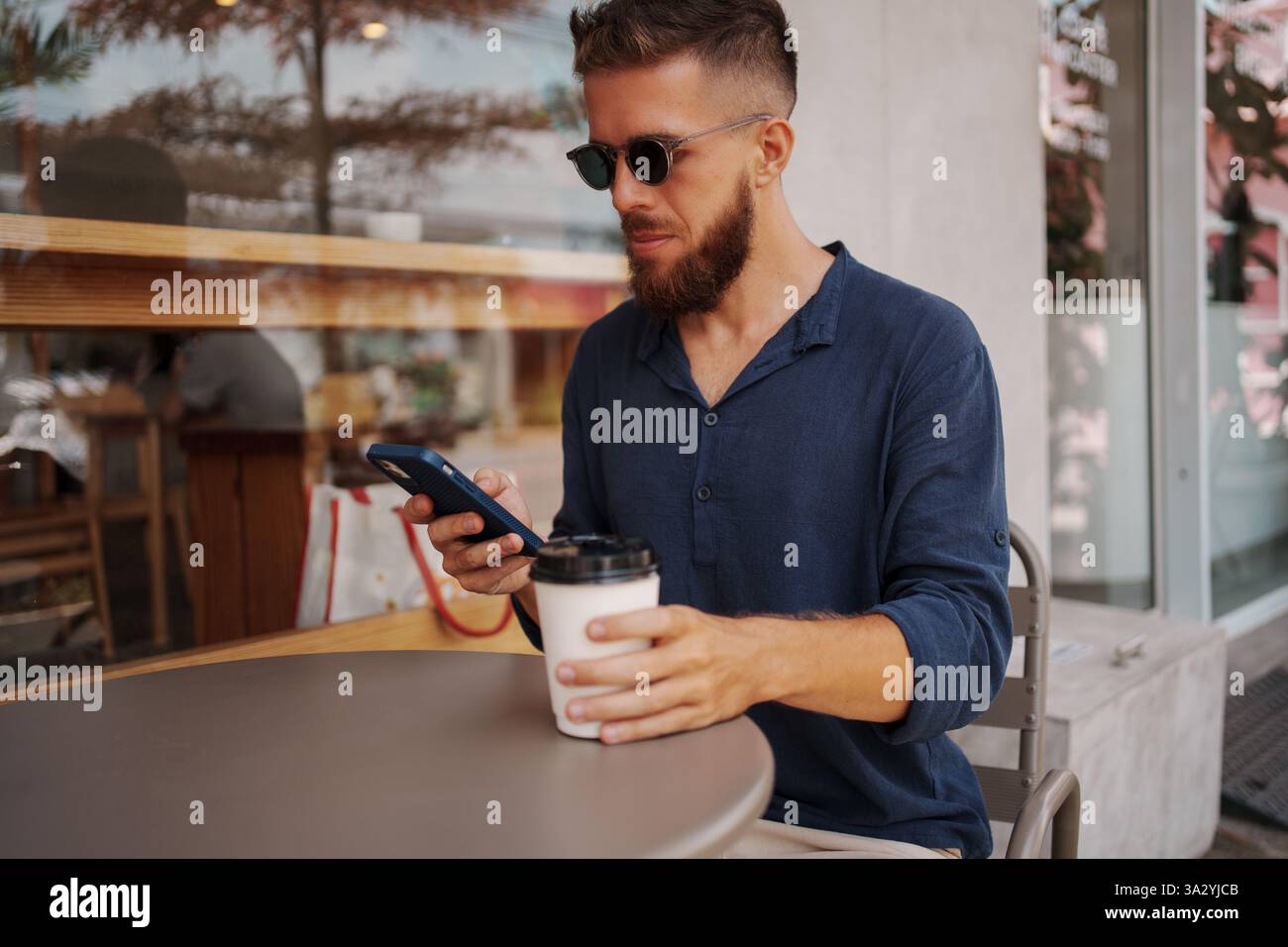 Stylish Man Enjoying Coffee While Using Phone at Caf Stock Photo