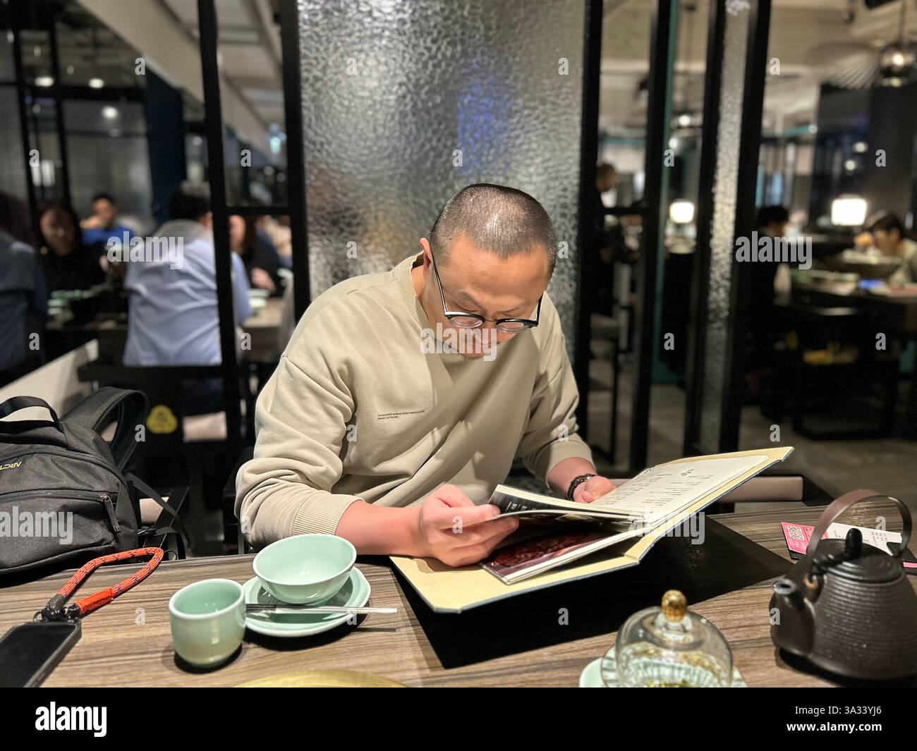 Taipei, Taiwan, Chinese Tourist at Table, inside, in Local Taiwanese Hot Pot Restaurant, 'Chin Huajiao » Zhongshan District, reading Menu - Smartphone Captured Stock Image