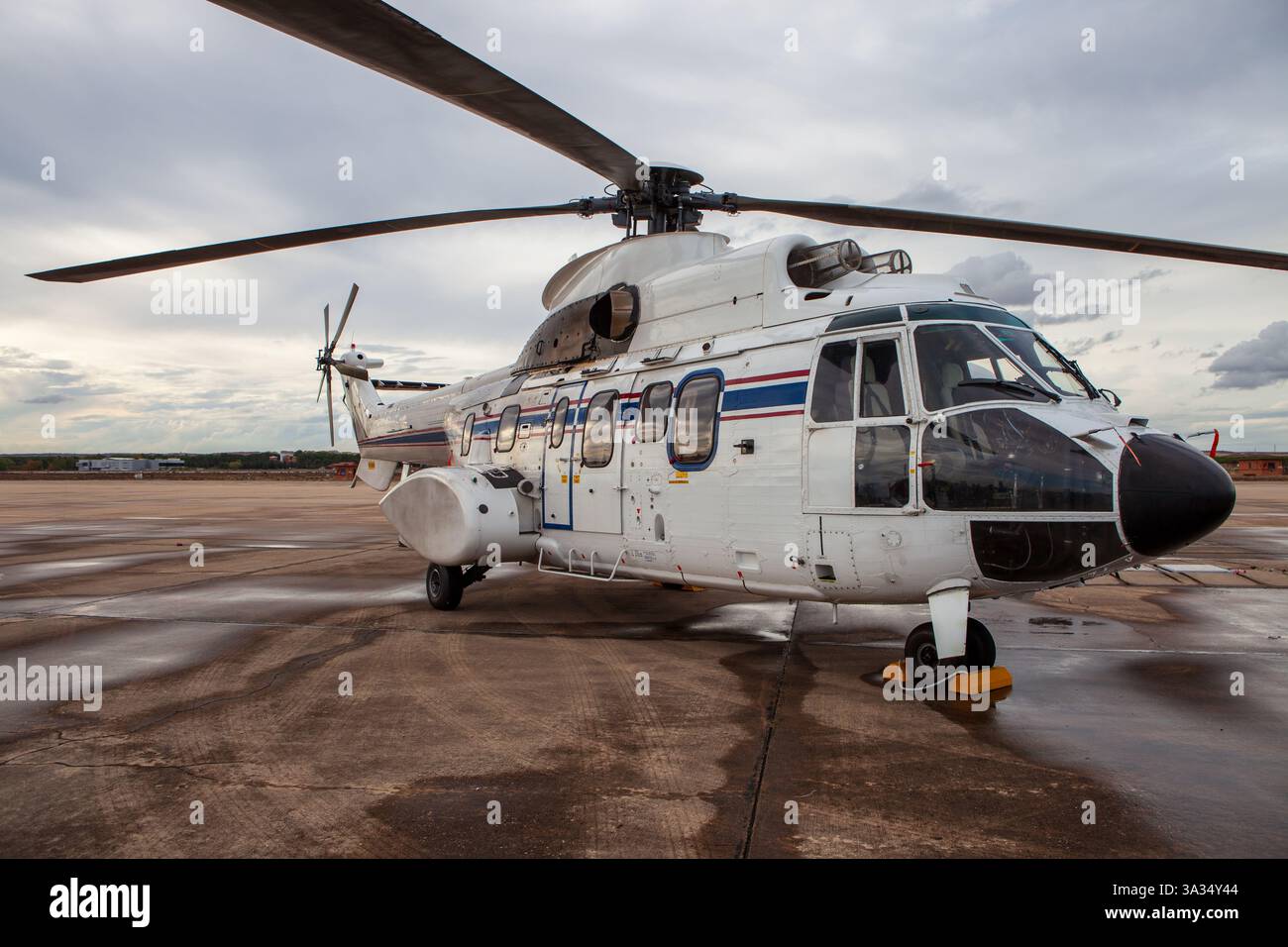 A white military helicopter with blue and red stripes is parked on the ...
