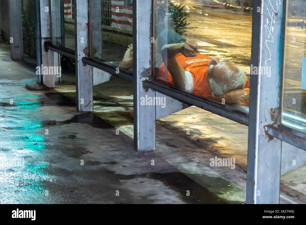 Homeless Bus Stop a homeless person lying sleeping on a bench a public bus station in the ...
