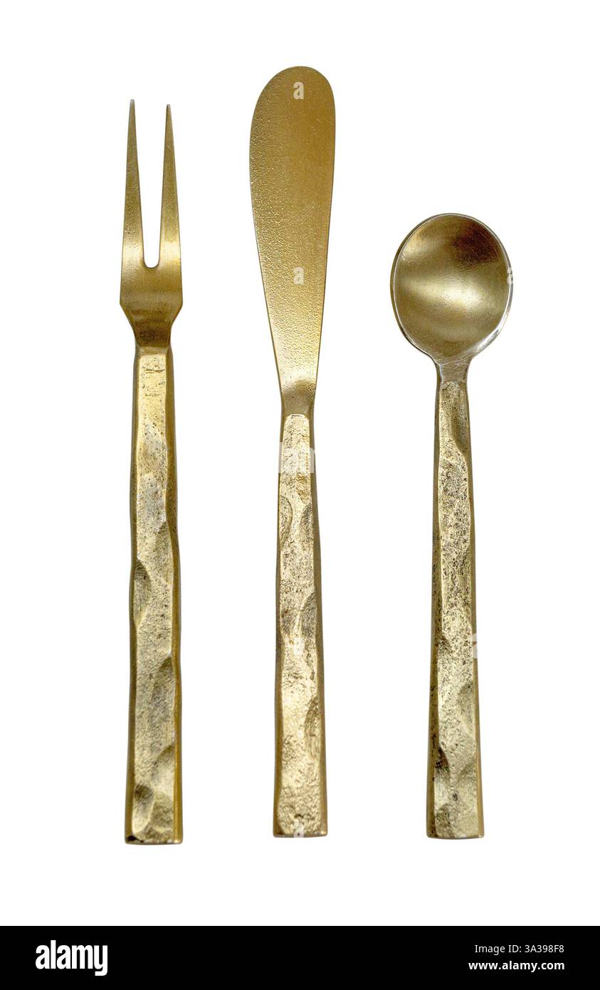 Golden fork, knife, and spoon with textured handles arranged on a white background, creating a visually appealing culinary composition Stock Photo
