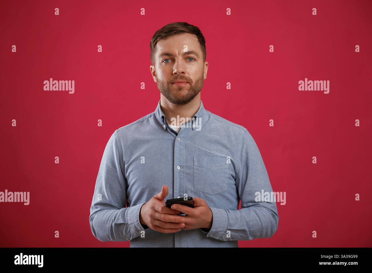 Black smartphone in hands. Man is standing against background in the studio. Stock Photo