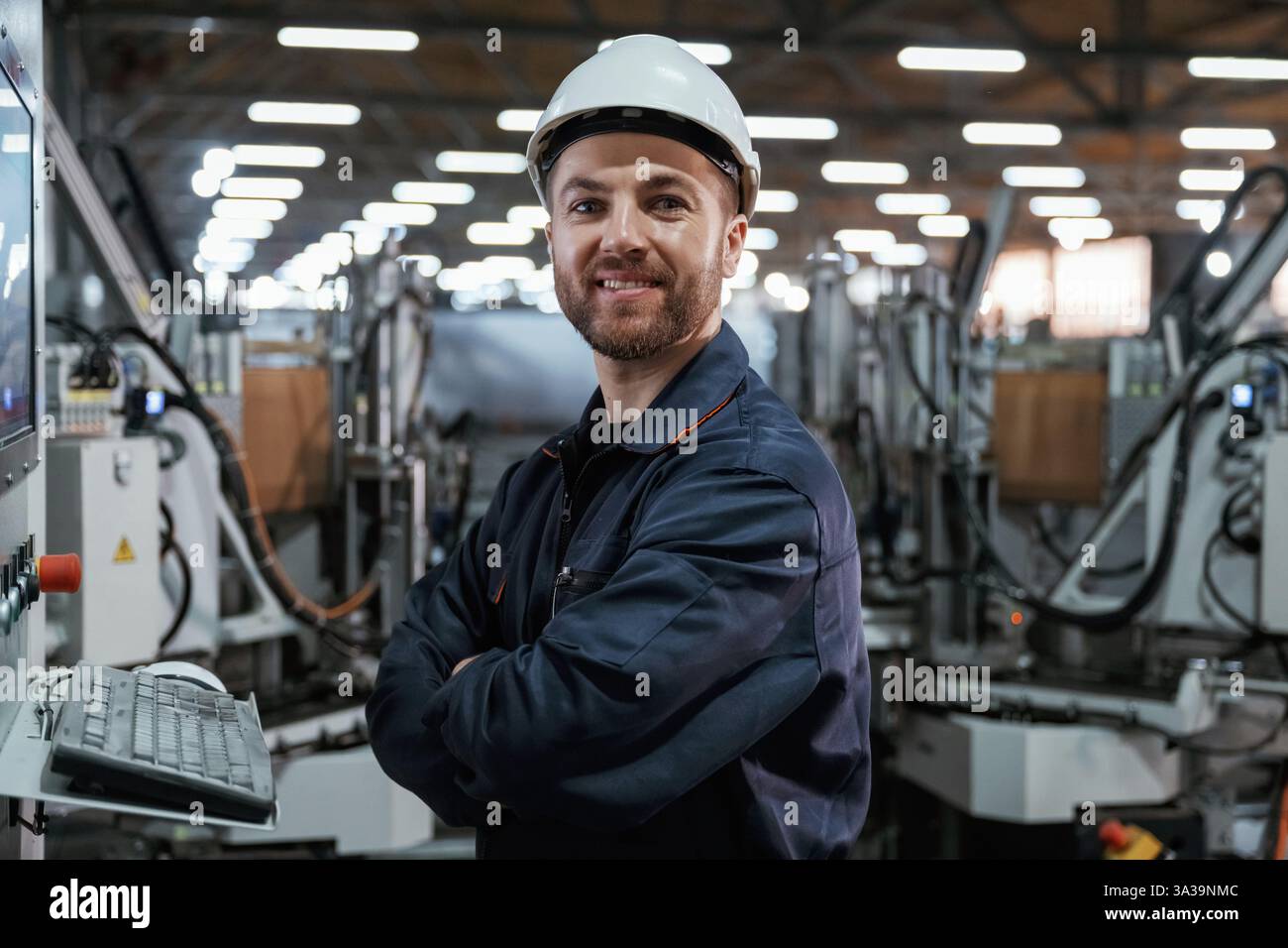 Using equipment, operator. Factory worker is indoors with hard hat. Stock Photo