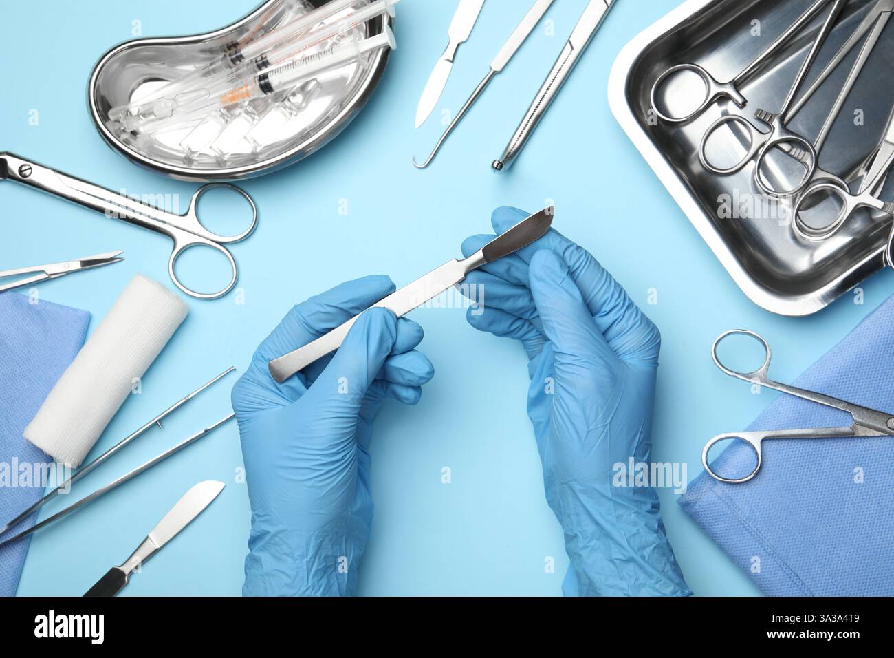Doctor with different surgical tools on light blue background, top view ...