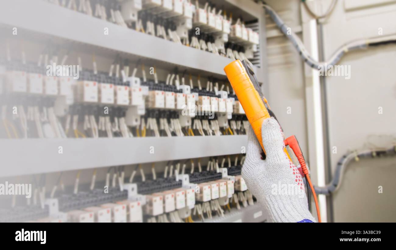Electrical engineer checking the operation of electrical control cabinet, maintenance concept. Stock Photo