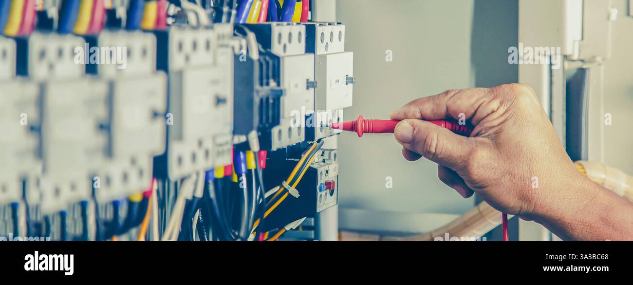 Electrical engineer checking the operation of electrical control cabinet, maintenance concept. Stock Photo