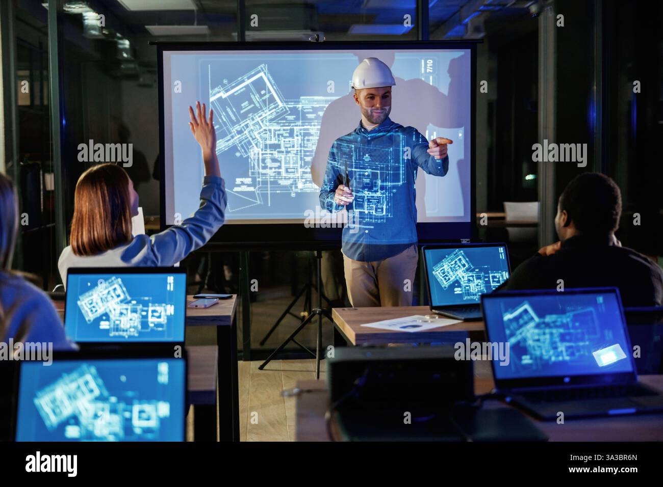 Male architect is showing construction site project on blue projector for people. Stock Photo
