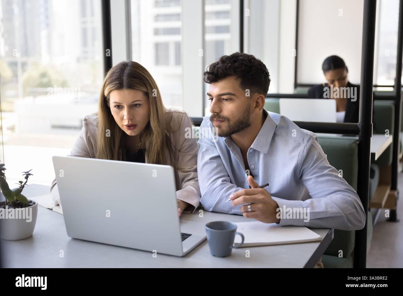 Two colleagues working together, reviewing information, analyzing data using laptop Stock Photo