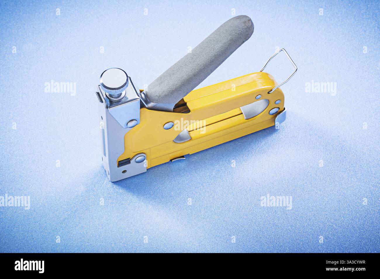 Yellow metal construction stapler on blue background top view Stock Photo