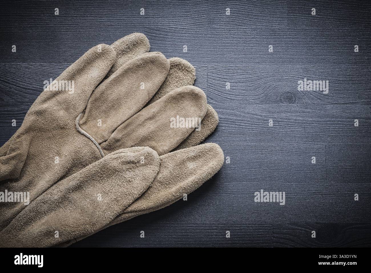 Two protective gloves on dark wood board Stock Photo