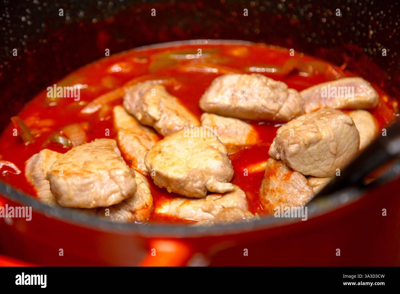 Pork pieces in pan with tomato and pepper sauce Stock Photo