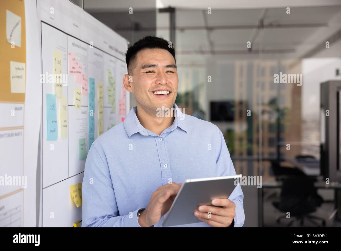Positive successful Asian project manager working with tablet Stock Photo