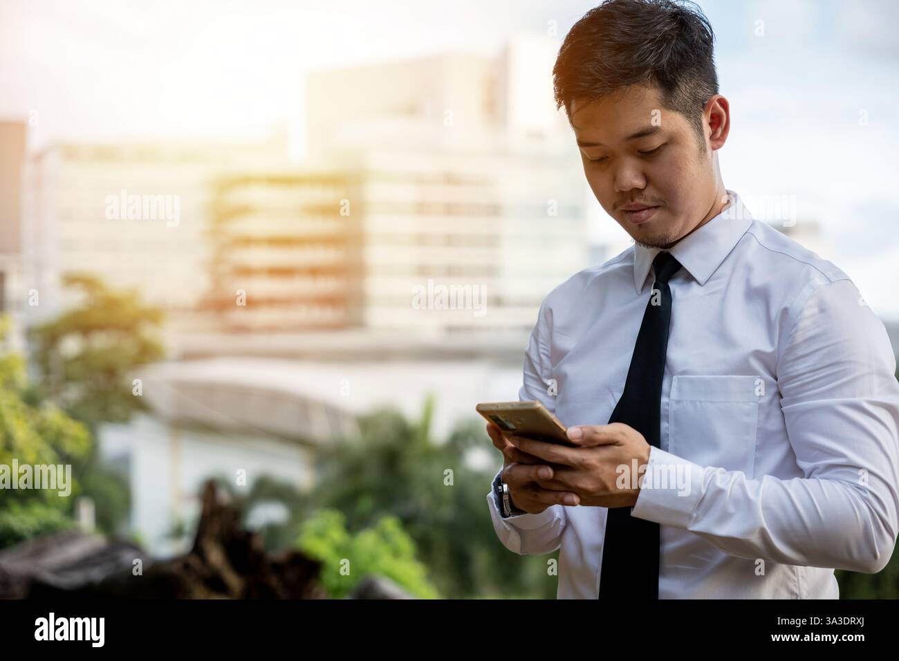 Successful Asian man, software developer, smiles testing app. Director outside office, serious about Stock Photo