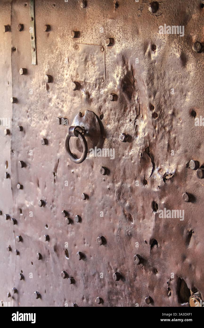 A detailed close-up of a weathered metal door featuring a rusty texture and iron elements, conveying a sense of history and rustic craftsmanship. Stock Photo
