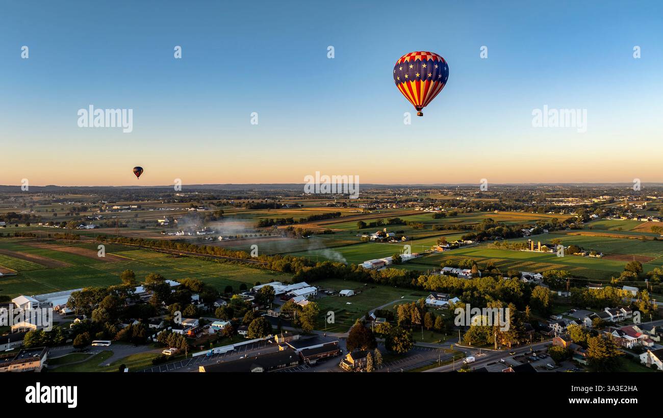 Hot air balloons float gracefully in the clear sky above a scenic ...