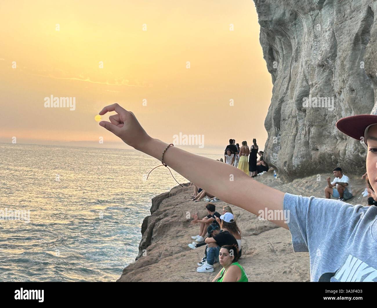 Optical illusion of a boy holding the sun in his fingers Stock Photo