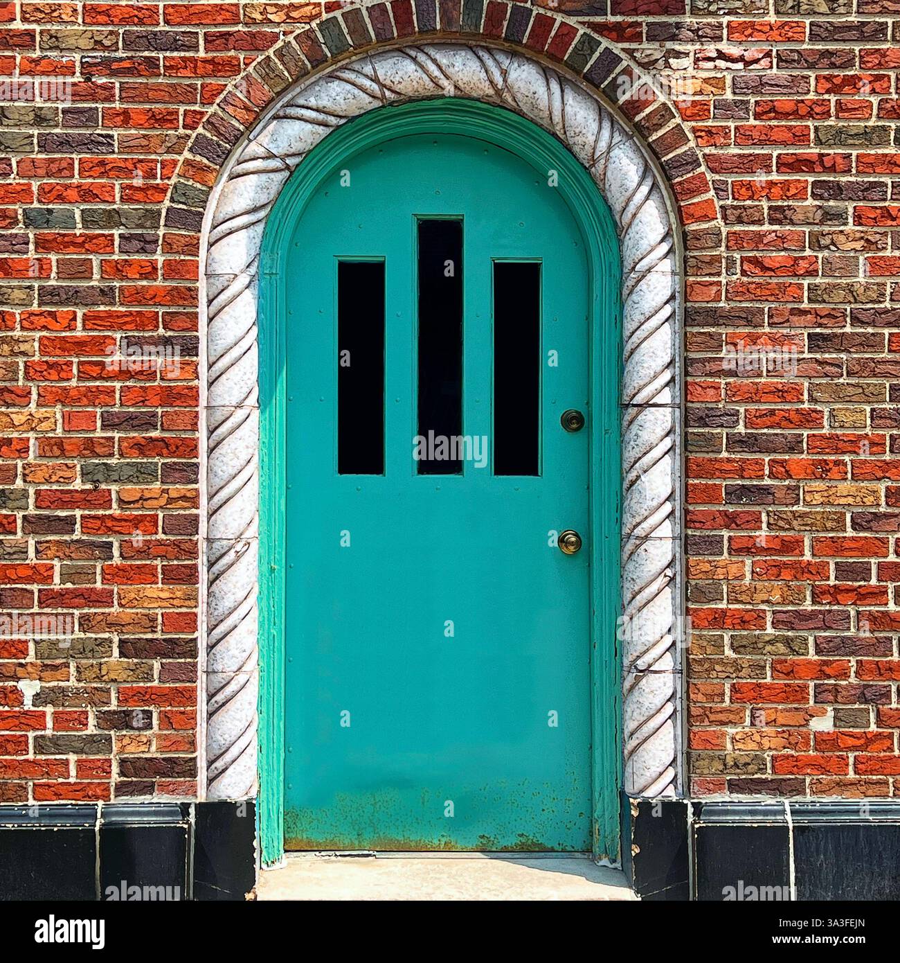 Vibrant mint green arched door set within a multicolored brick facade, framed by a decorative twisted stone archway. - Smartphone Captured Stock Image