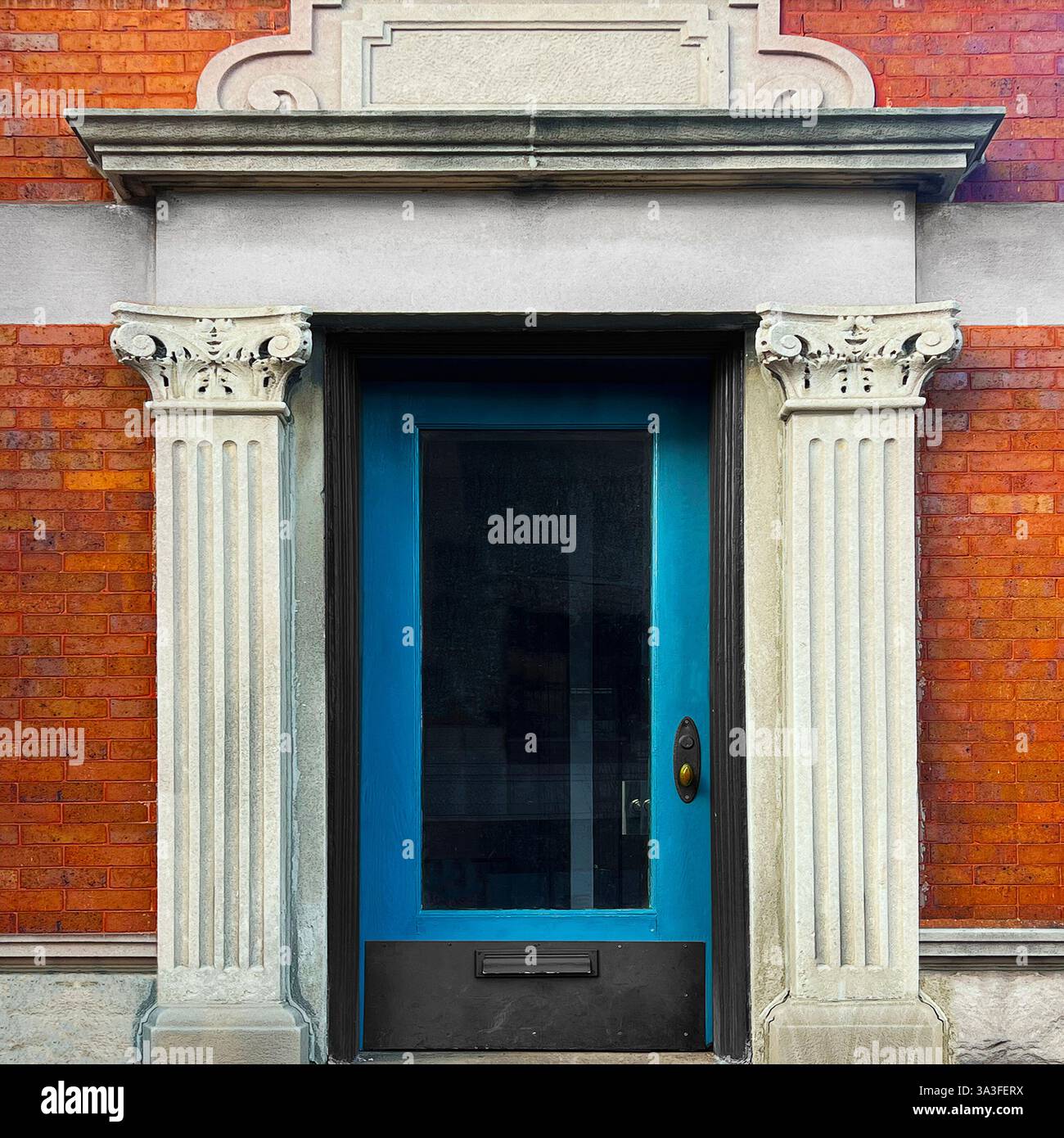 Elegant blue glass-paneled door framed by fluted Corinthian columns and an ornate stone pediment, set within a historic orange brick facade. - Smartphone Captured Stock Image