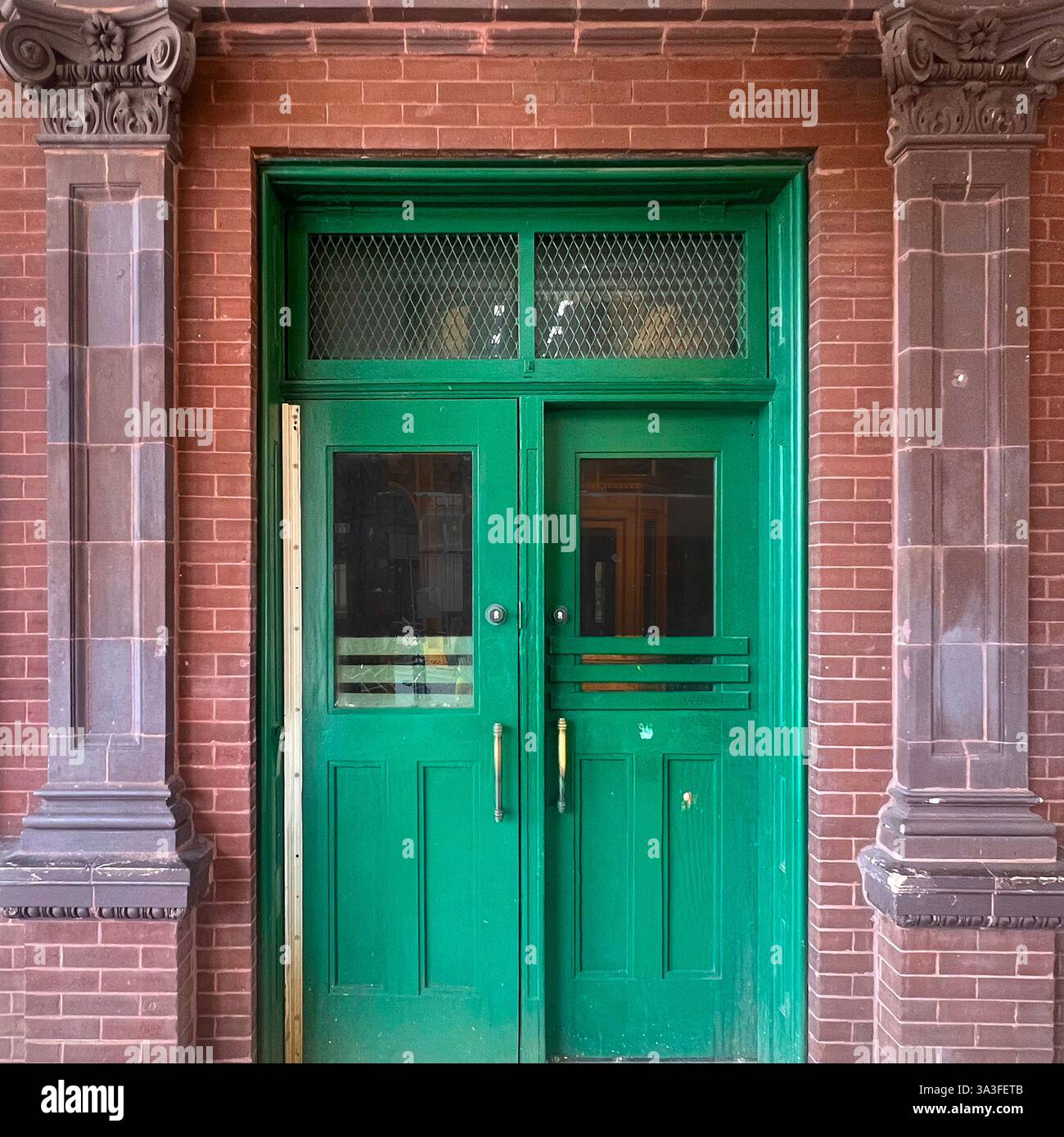 Historic Chicago subway station entrance featuring green wooden double doors, with wire glass, and fluted stone columns. - Smartphone Captured Stock Image