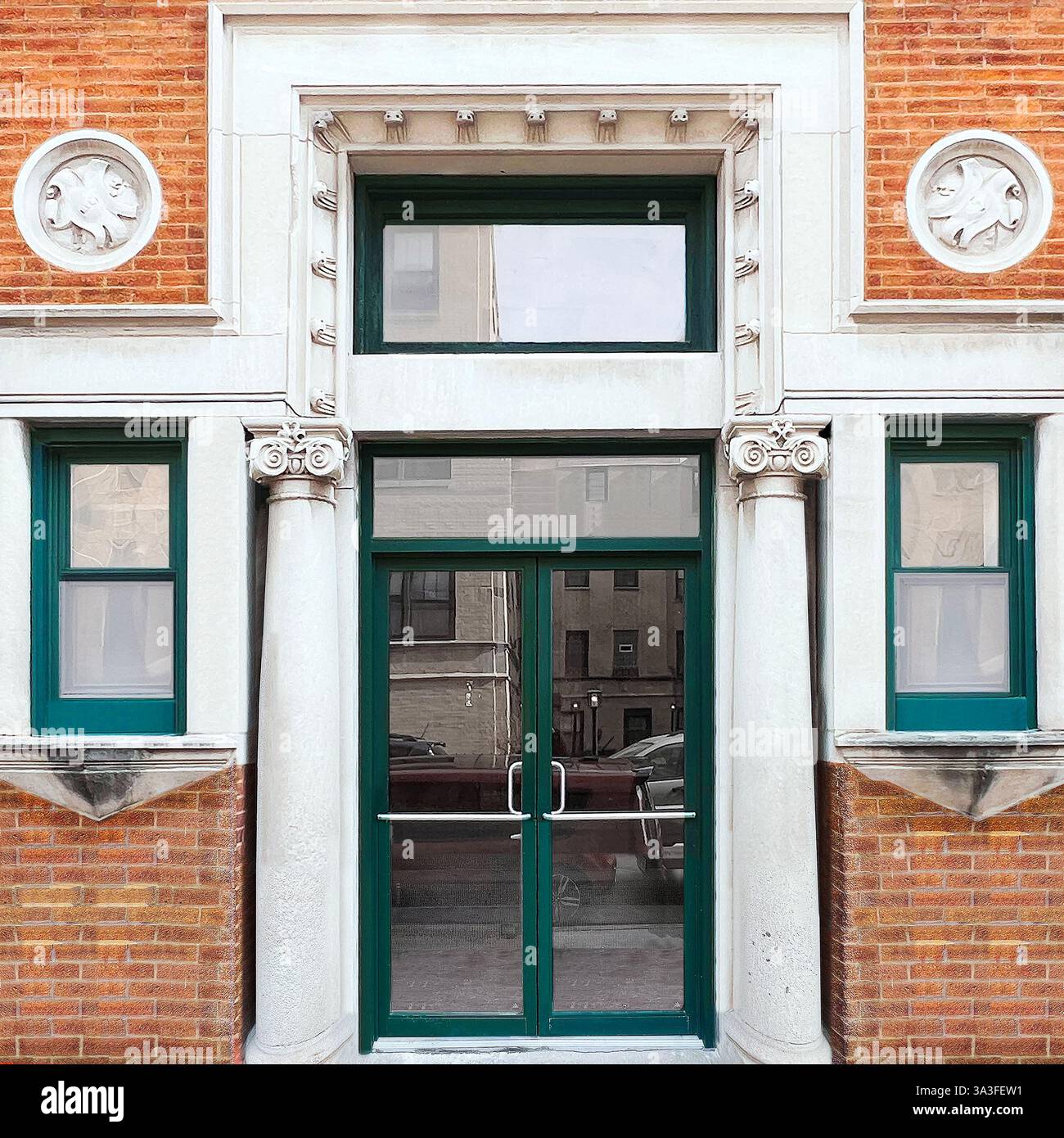 Green glass double doors within limestone, orange brick facade, Corinthian columns, decorative medallions and neoclassical architectural details. - Smartphone Captured Stock Image