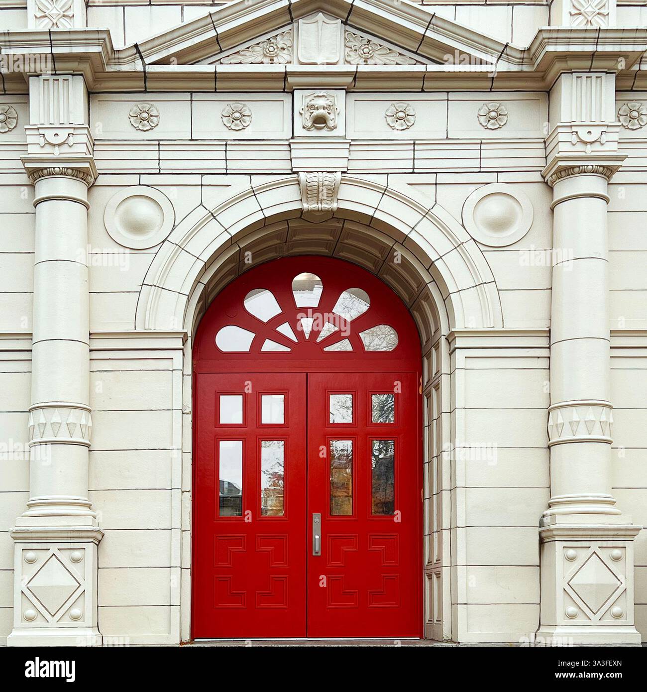 Grand red arched double doorswithin an ornate neoclassical facade, featuring intricate stone carvings, decorative columns. - Smartphone Captured Stock Image