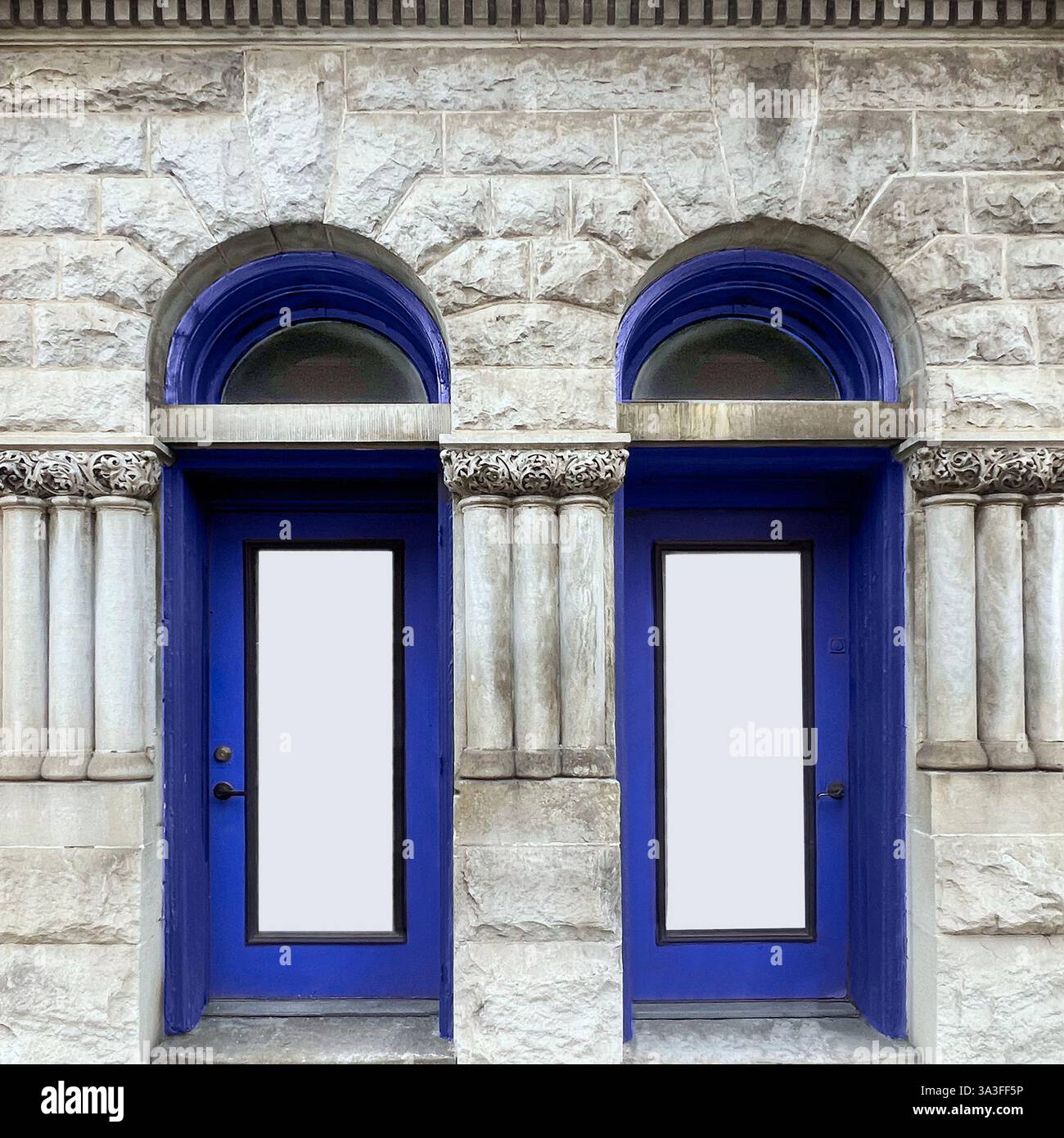 Historic stone building with striking blue double doors framed by classical columns and arched transom windows. - Smartphone Captured Stock Image