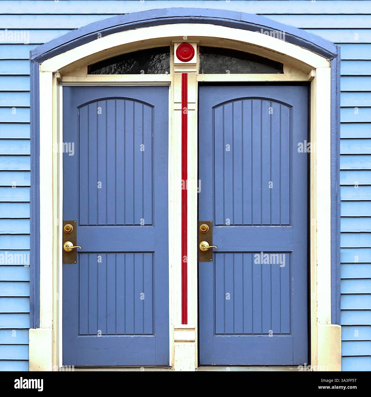 Symmetrical blue double doors with an arched transom, framed by white trim and red decorative accents on a blue sliding facade. - Smartphone Captured Stock Image