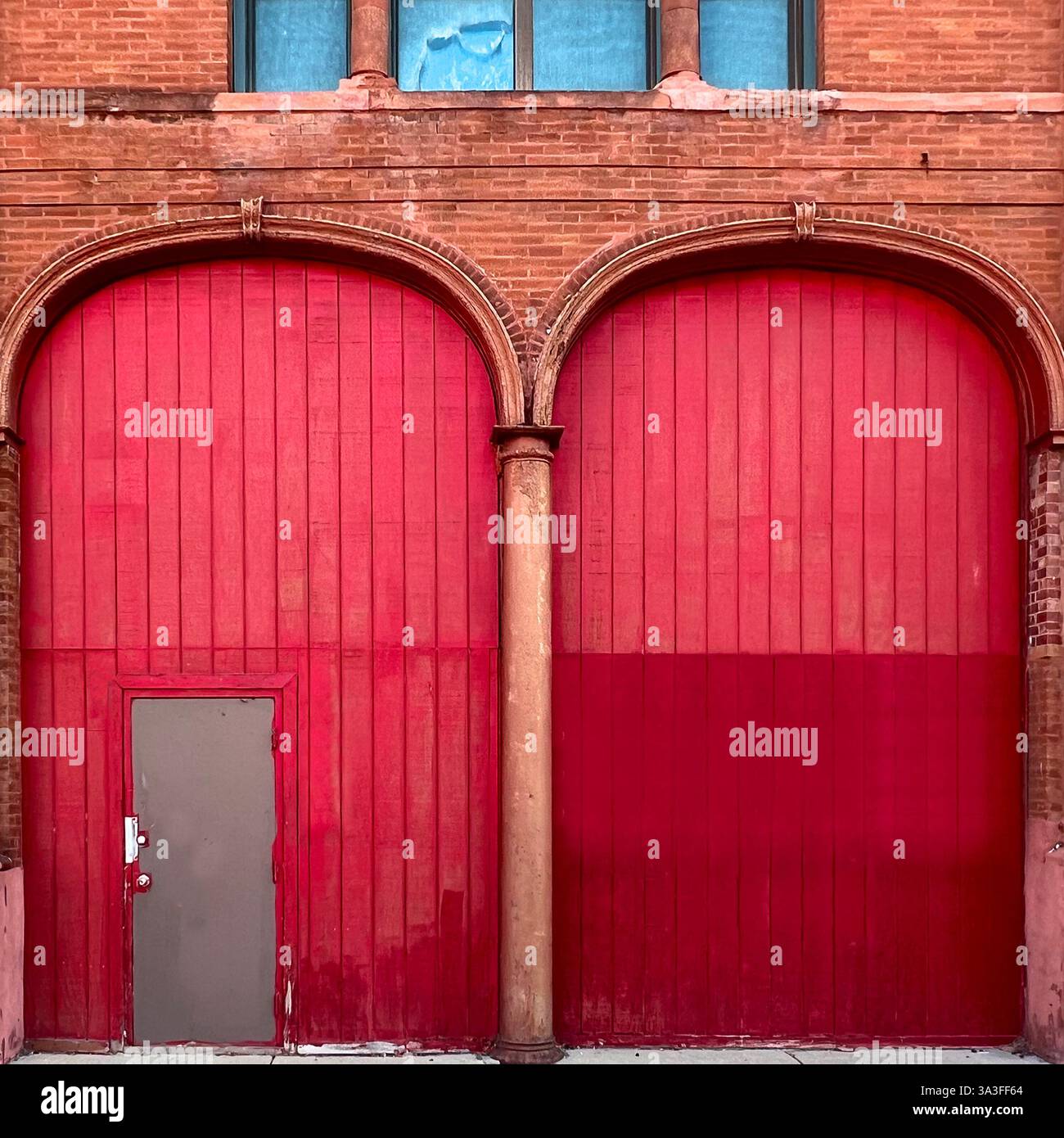 A striking red architectural facade featuring grand arched doorways ...