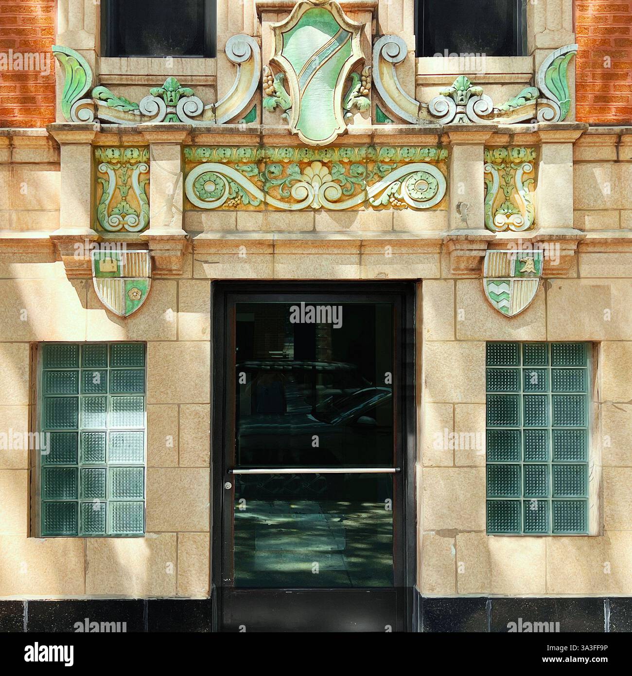 An ornate building entrance featuring intricate green and gold glazed terracotta detailing, set against a yellow facade. - Smartphone Captured Stock Image