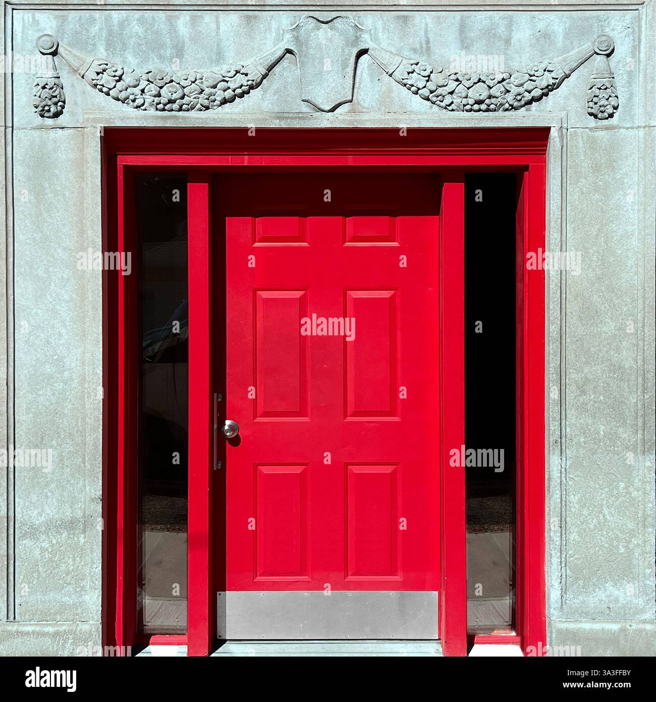 Red doors within a grand stone facade, featuring intricate carved garland details. - Smartphone Captured Stock Image