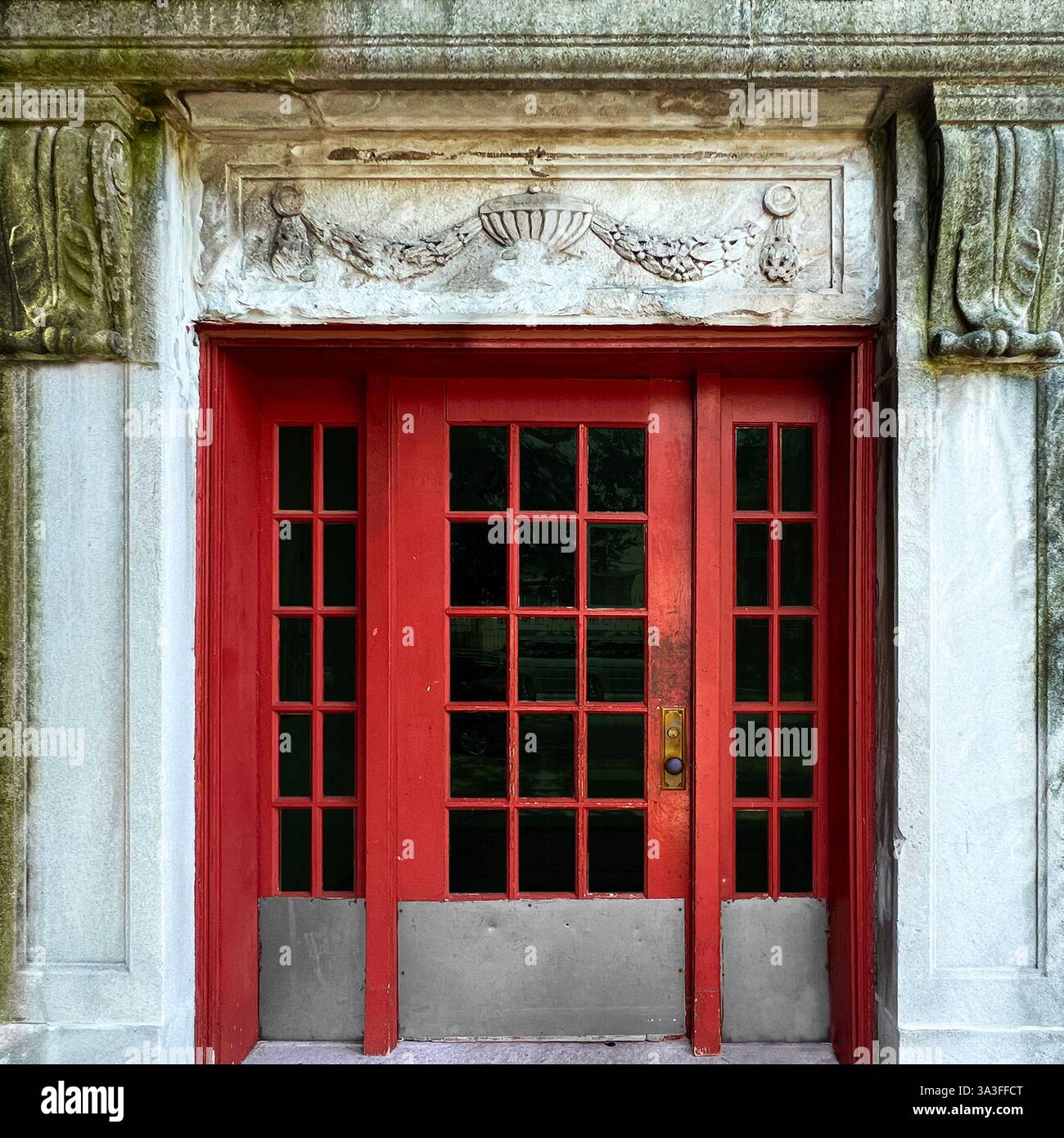 Red vintage doorway with intricate glass panes, framed by weathered stone carvings, showcasing the timeless architectural elegance of Chicago - Smartphone Captured Stock Image