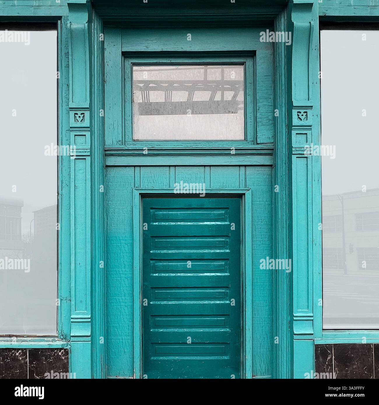 A vintage turquoise wooden door with intricate architectural details, framed by large glass windows, reflecting Chicago's historic urban charm. - Smartphone Captured Stock Image