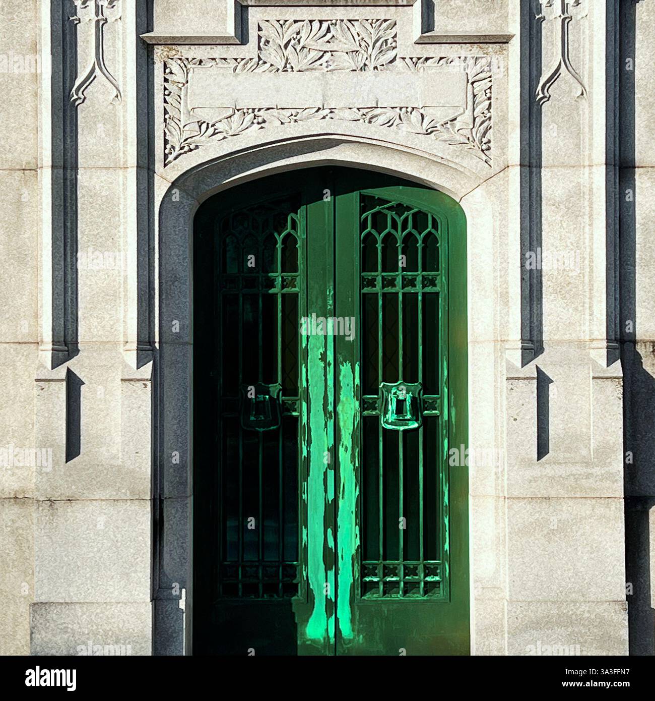 A green metal door marks the entrance to a tomb, framed by detailed stonework. - Smartphone Captured Stock Image