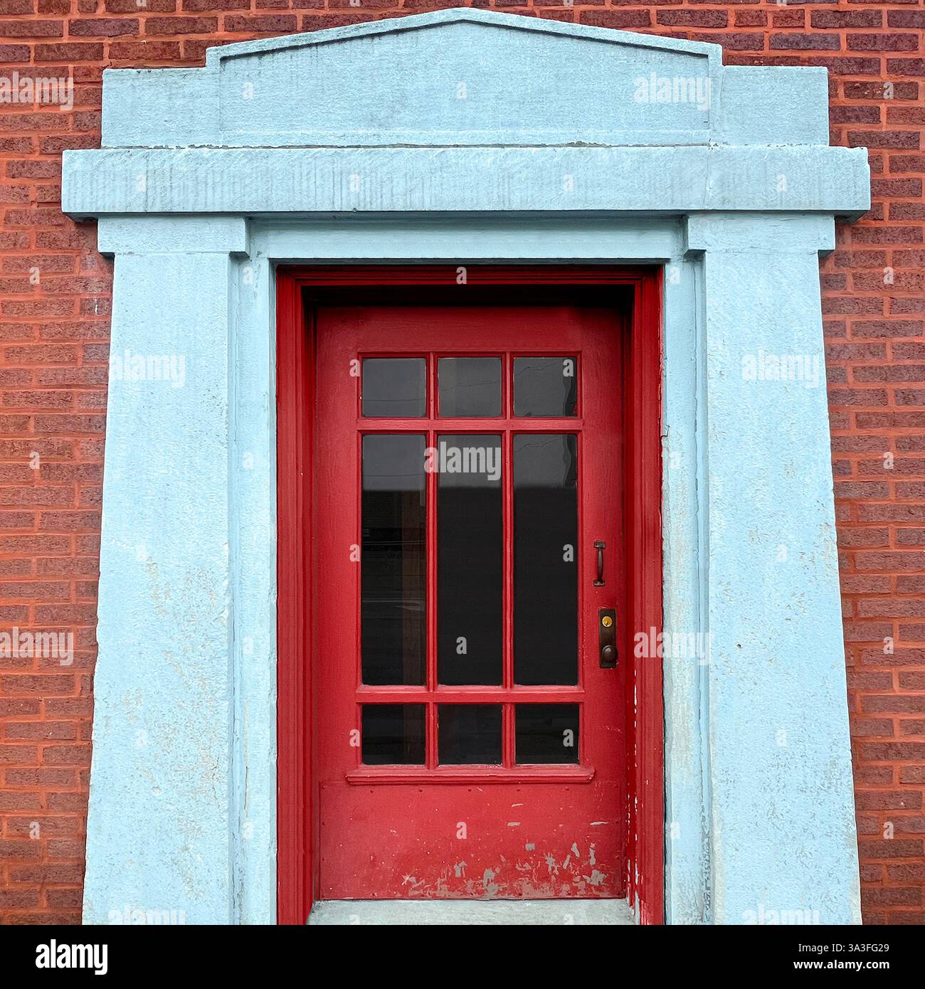 Red door framed by a weathered stone entrance against a classic red brick wall. - Smartphone Captured Stock Image