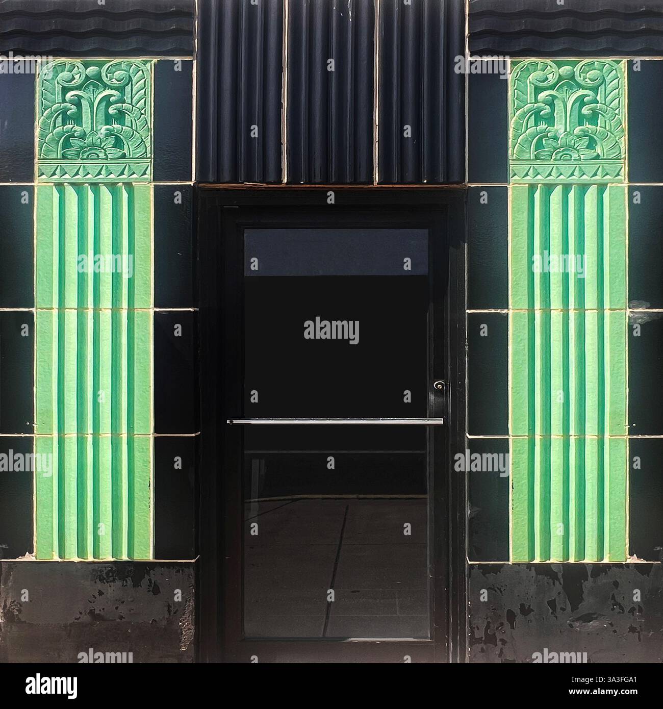 Historic doorway framed by striking green and black Art Deco ceramic tiles, featuring detailed ornamental motifs, Chicago - Smartphone Captured Stock Image
