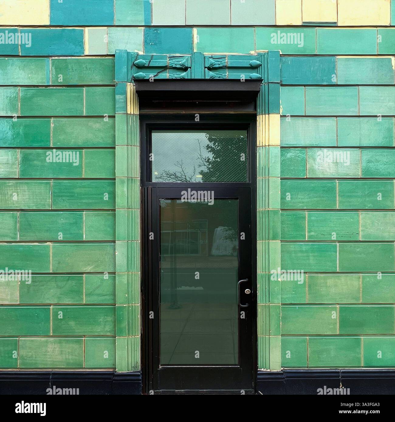Art Deco doorway with vibrant green glazed ceramic tiles and black framed glass door in Chicago - Smartphone Captured Stock Image