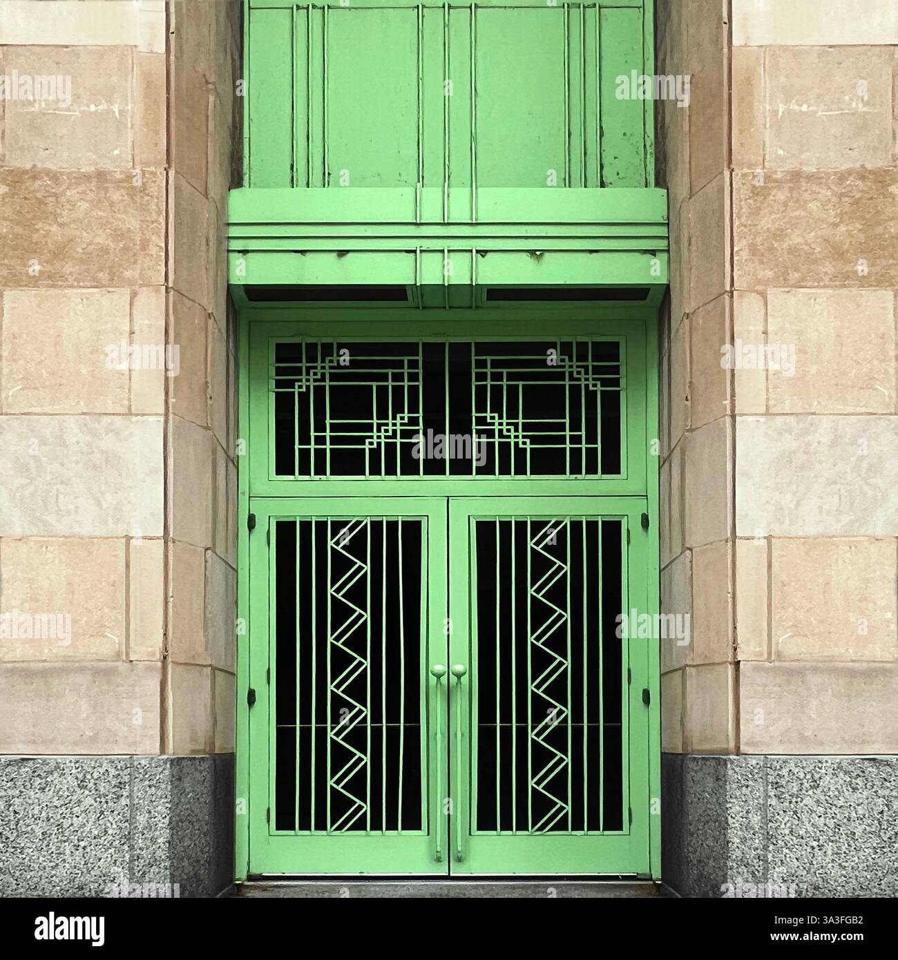 Art Deco doorway featuring symmetrical geometric metalwork in mint green, framed by stone walls on a historic building facade in Chicago - Smartphone Captured Stock Image