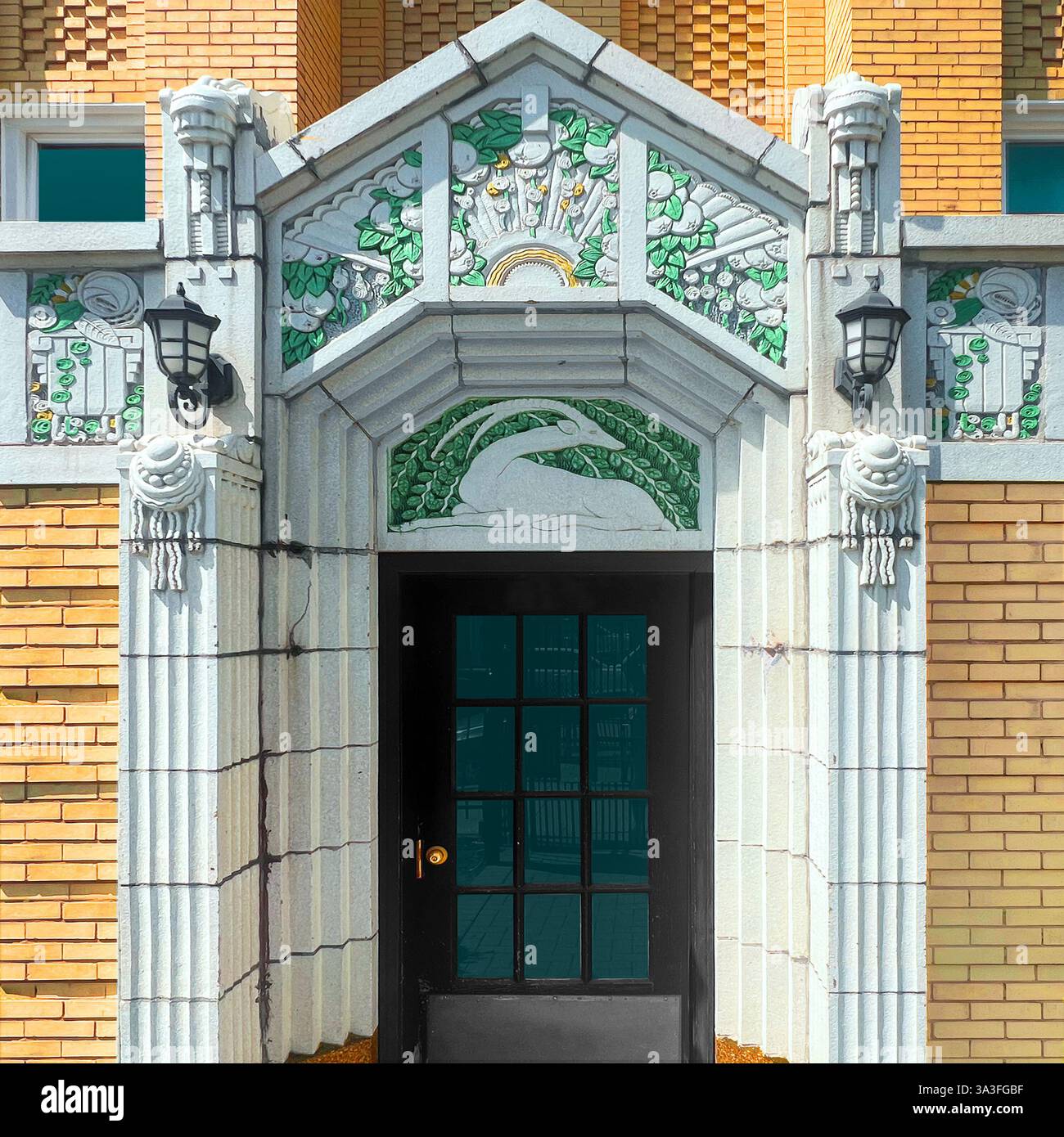 Art Deco entrance featuring ornate terra cotta detailing with floral and animal motifs, decorative green and gold accents, and classic brick facade. - Smartphone Captured Stock Image