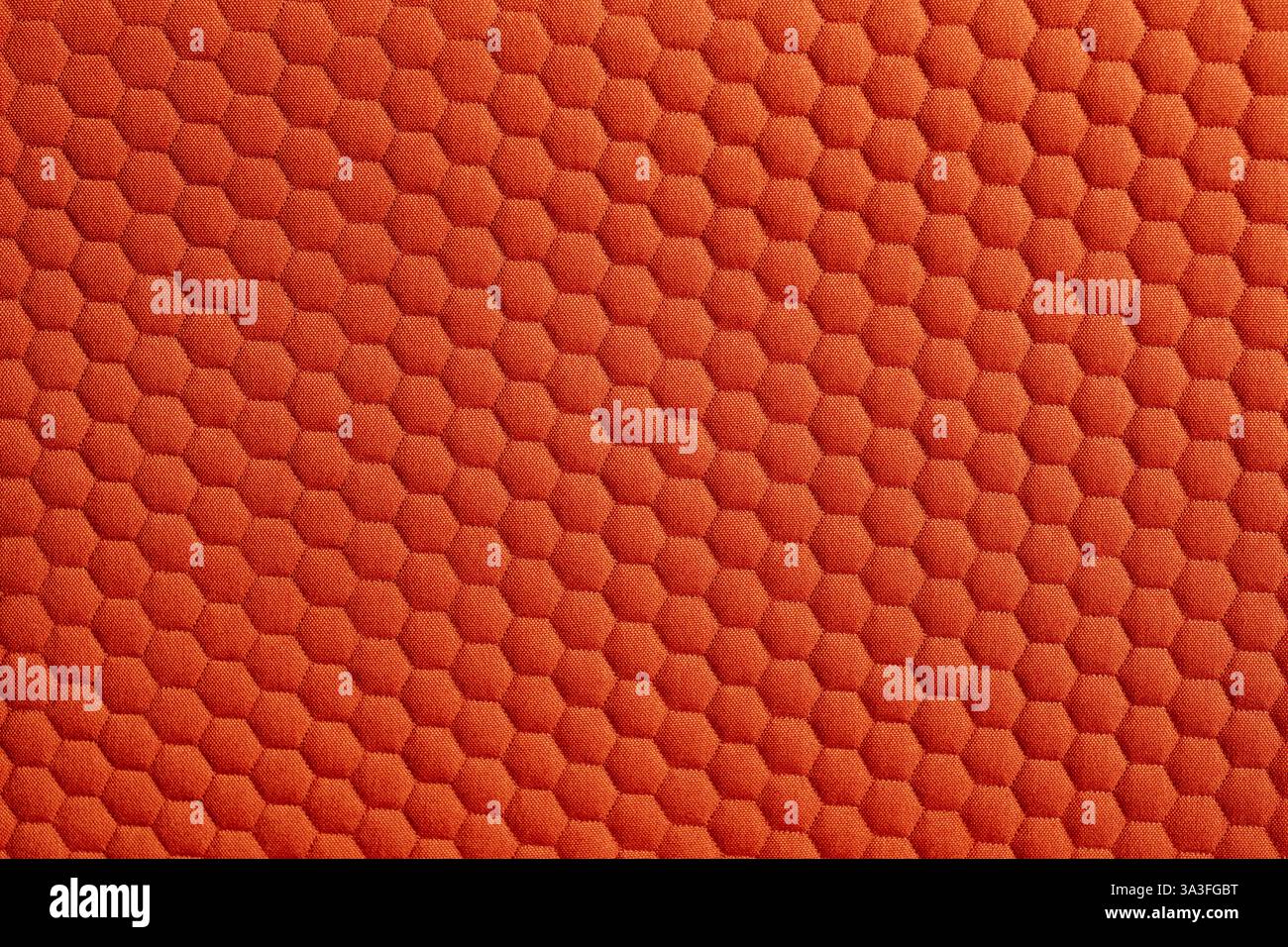 Close up of a vibrant orange fabric featuring a textured honeycomb pattern creating a visually appealing and tactile surface Stock Photo
