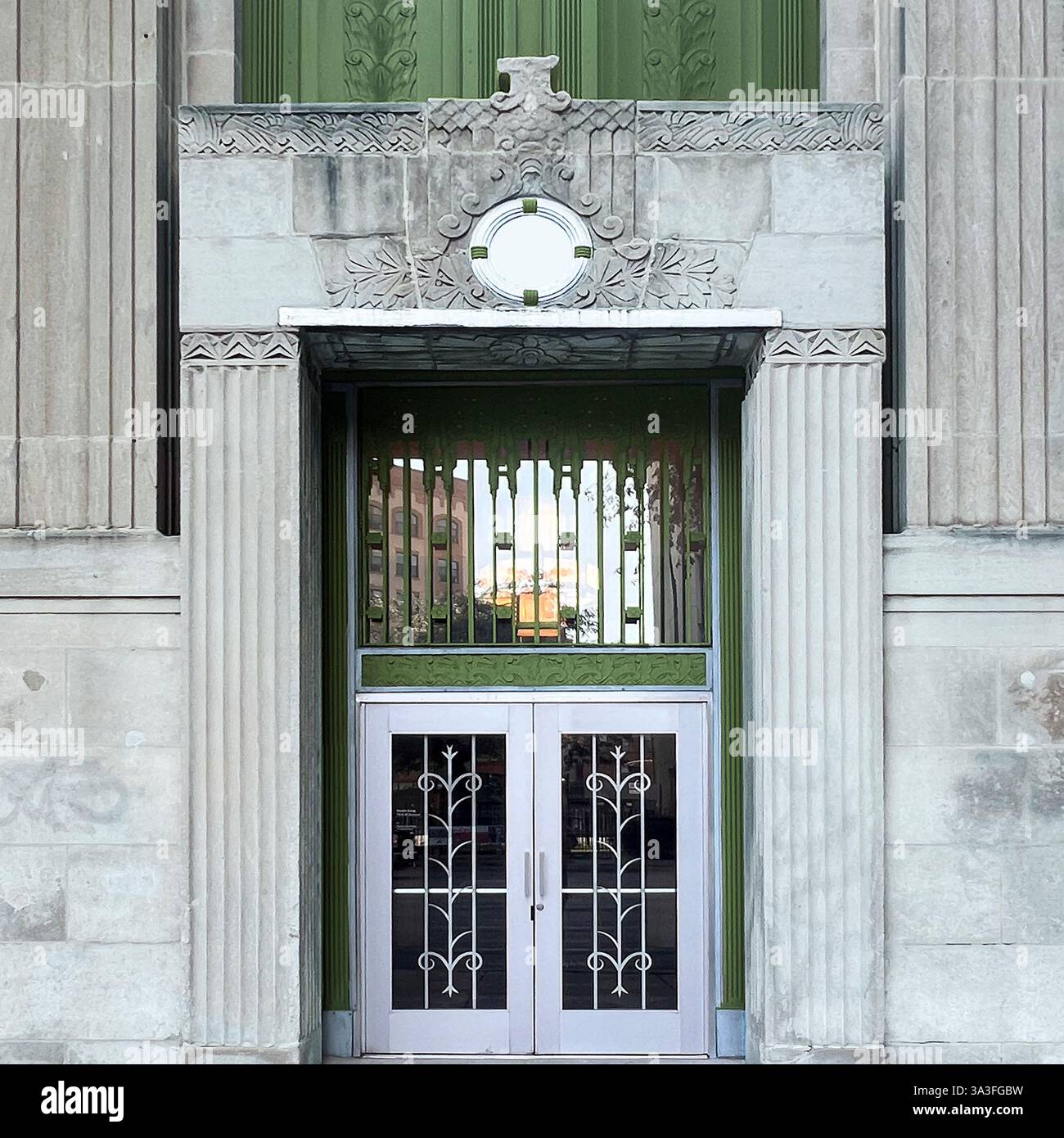 Art Deco doorway with decorative silver and green metal doors, and symmetrical columns in historic urban architecture. - Smartphone Captured Stock Image