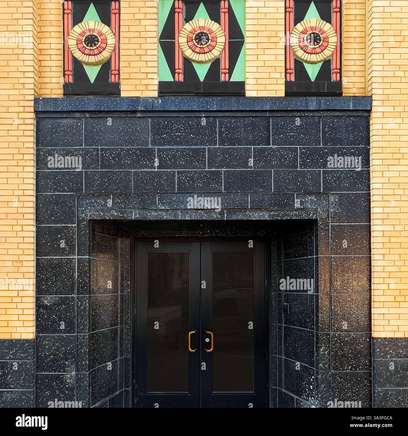 Art Deco entrance featuring polished black granite, colorful geometric floral motifs, and decorative brickwork in urban architecture. - Smartphone Captured Stock Image