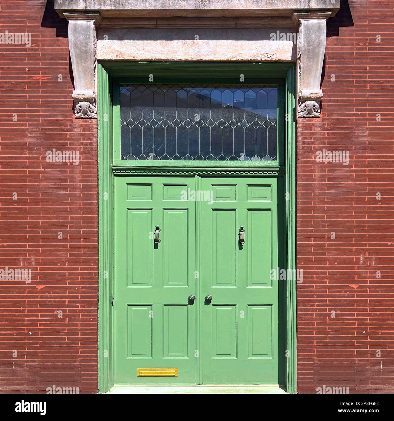 Mint-green vintage door with decorative stained glass window set in a vibrant brown brick facade in Chicago. - Smartphone Captured Stock Image