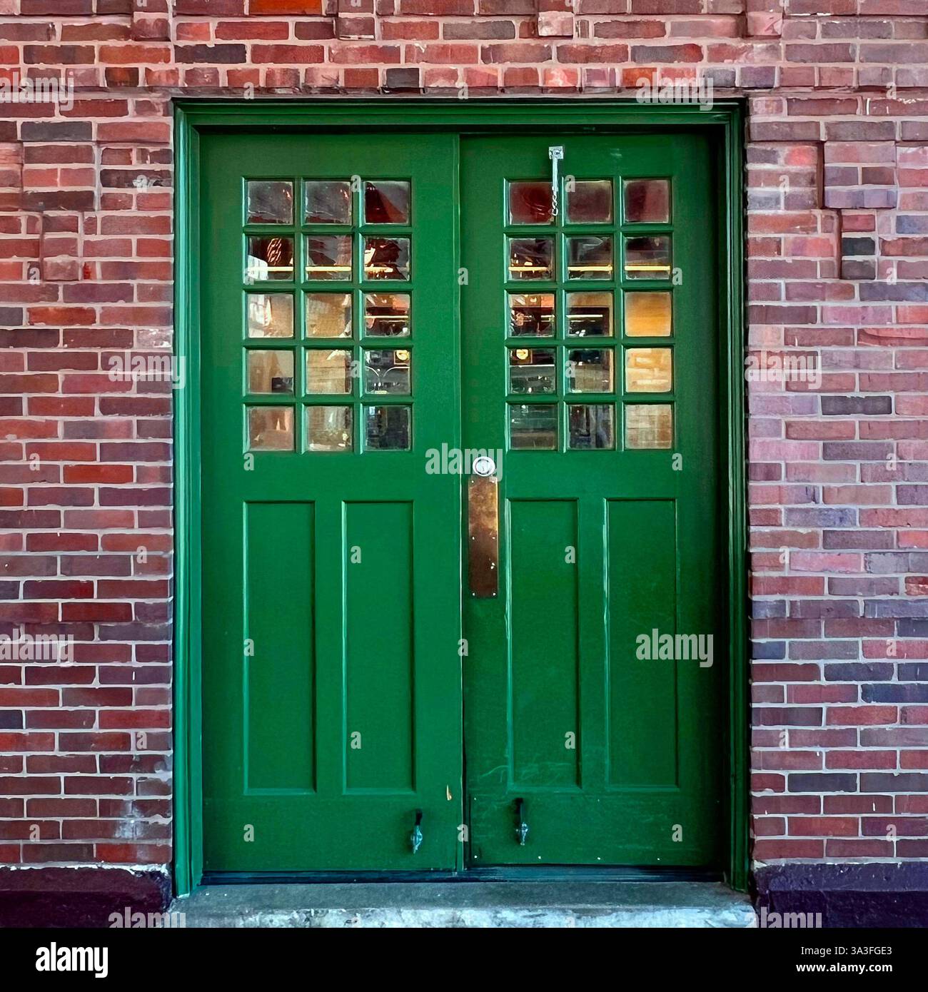 Green subway entrance door with glass panes set in a red brick wall in Chicago. - Smartphone Captured Stock Image