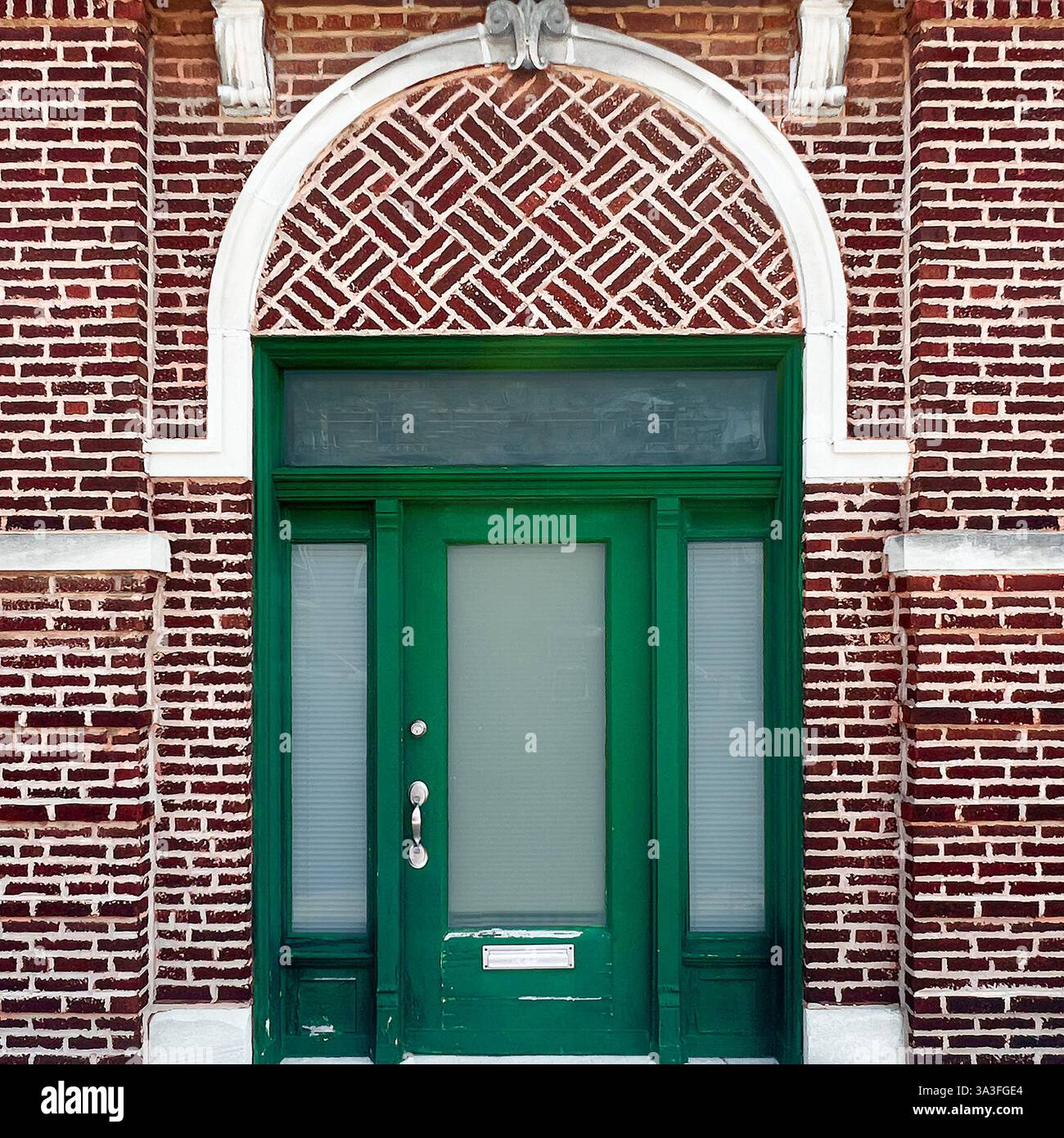 Green door with frosted glass set against a decorative red brick wall with a patterned archway in Chicago. - Smartphone Captured Stock Image