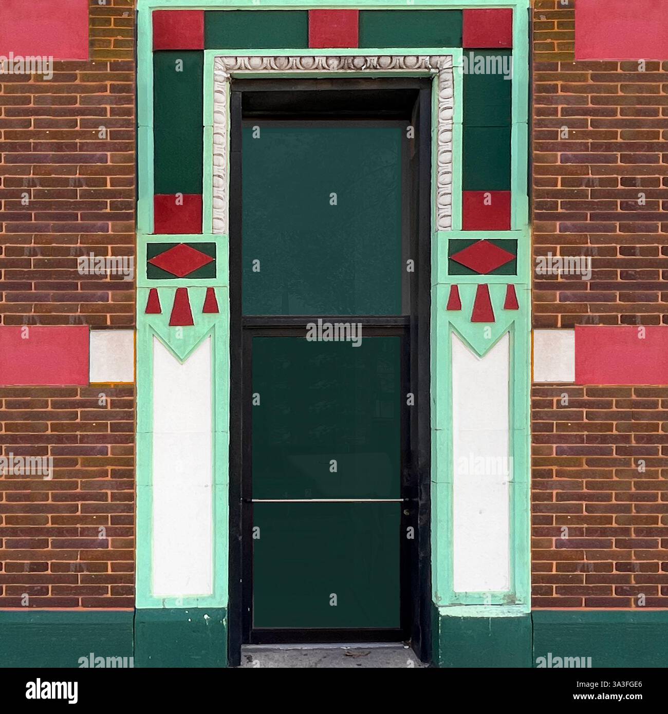 Art Deco urban doorway featuring glass door framed by vibrant geometric patterns in green, mint, red, and white, surrounded by brickwork. - Smartphone Captured Stock Image