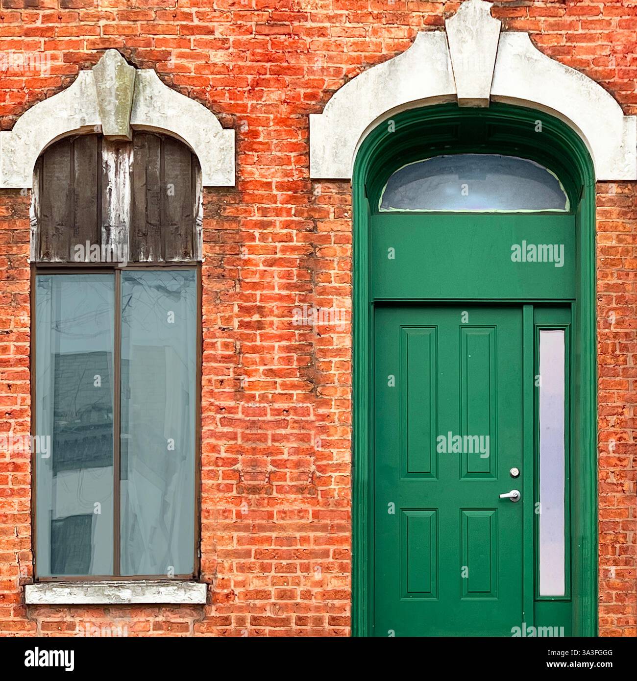 A bright green door with a modern vertical window stands out against the aged orange brick facade in Chicago - Smartphone Captured Stock Image