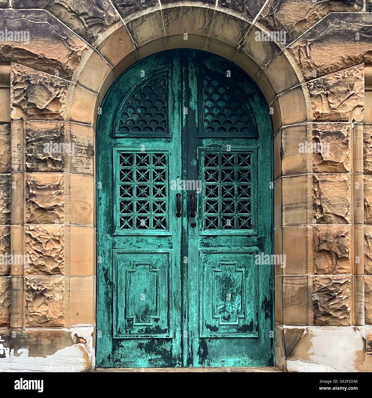 A weathered green patina metal door with intricate latticework set within a historic stone mausoleum entrance. - Smartphone Captured Stock Image