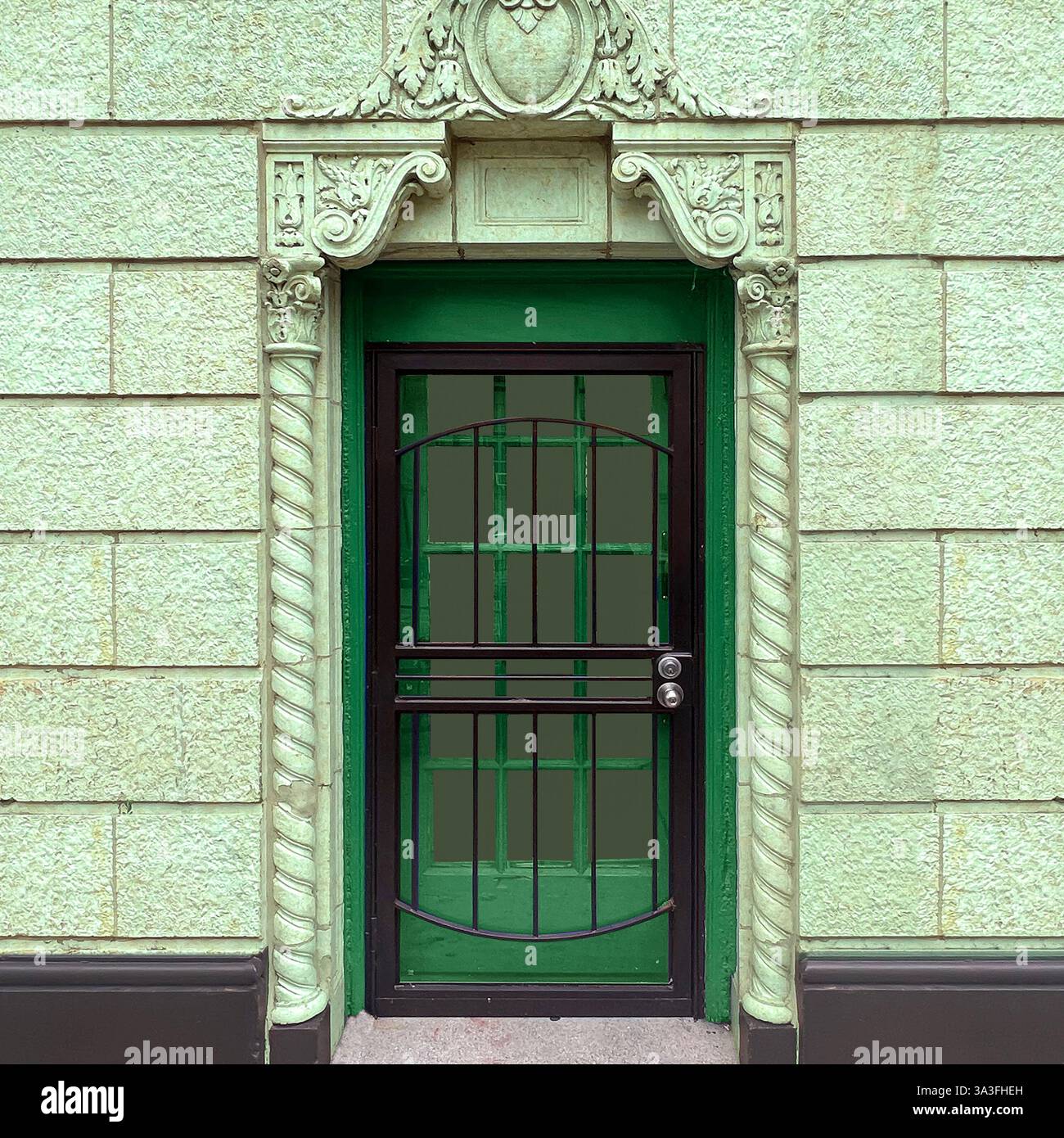 An ornate green doorway with intricate stone carvings and a wrought iron security door in Chicago. - Smartphone Captured Stock Image